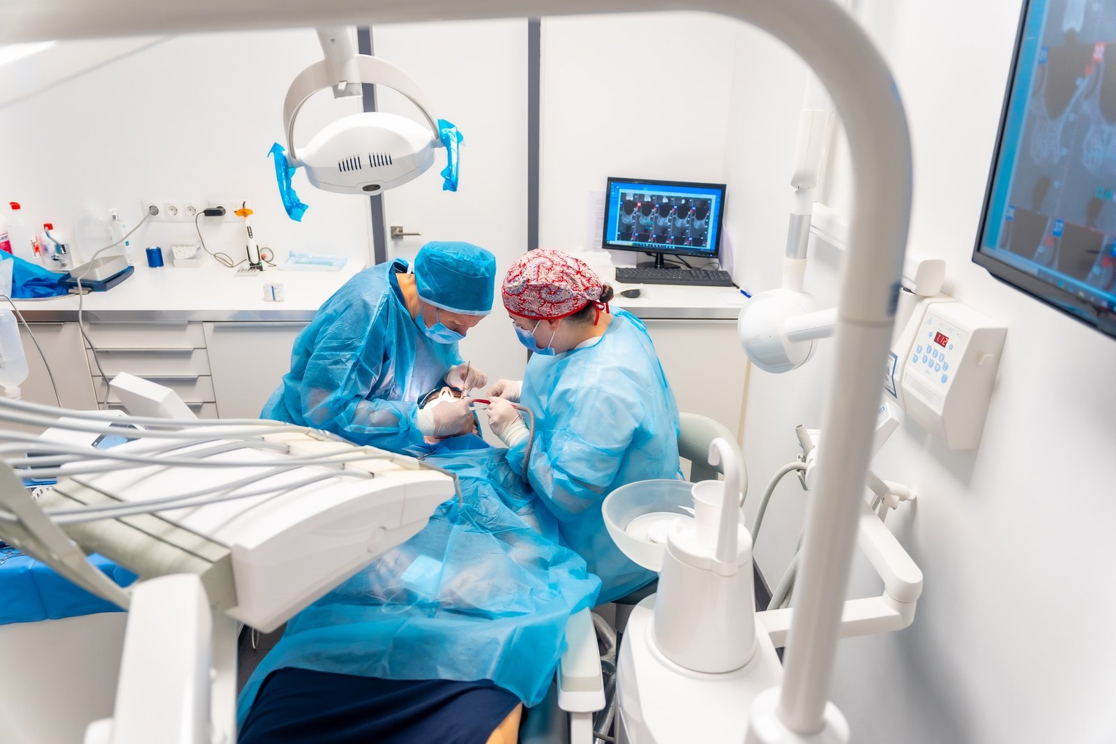 Dental clinic, detail of dentists with blue suits performing an implant, view from above operation