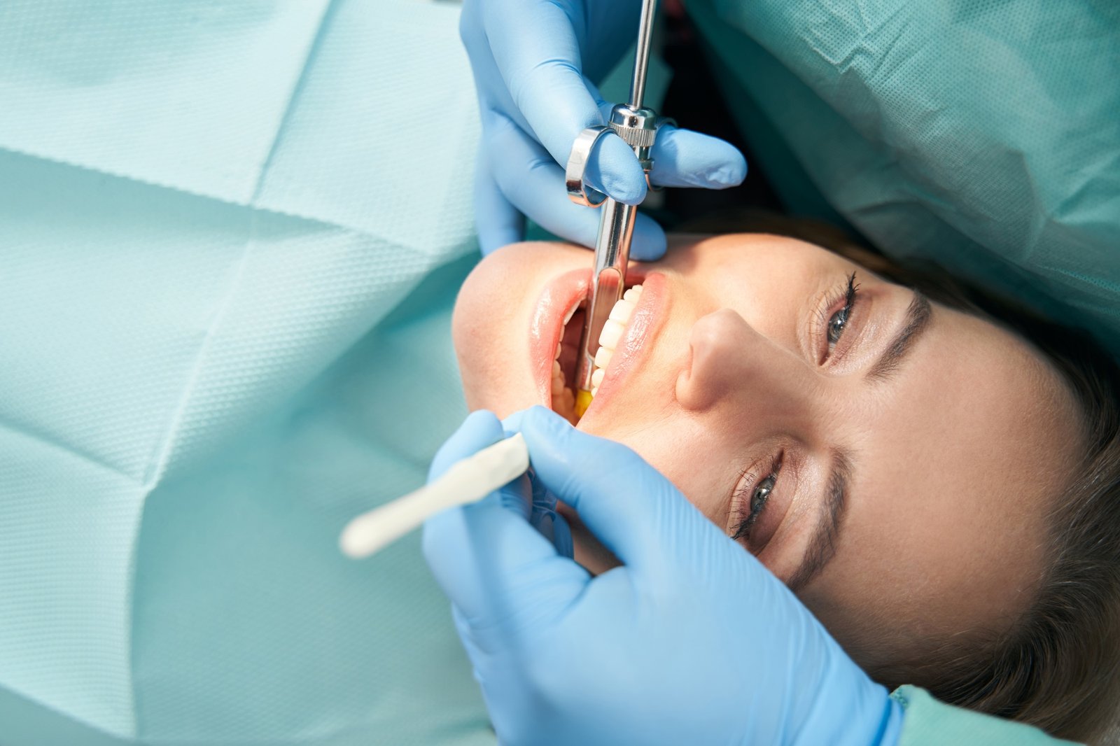 Dentist injecting anesthetic medicine into woman gum with syringe