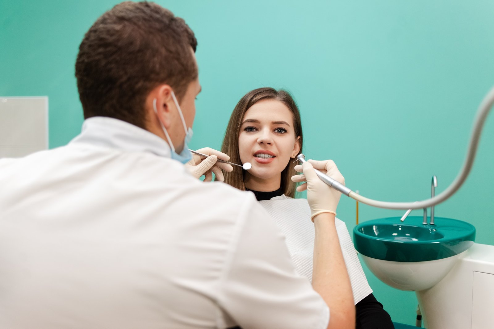 Dentist with a drill and a mirror is treating a patient teeth