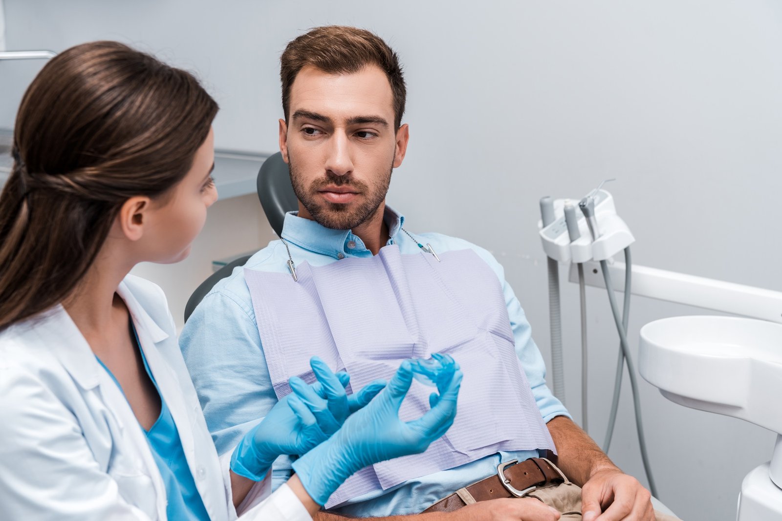 selective focus of patient looking at dentist with retainer in hands