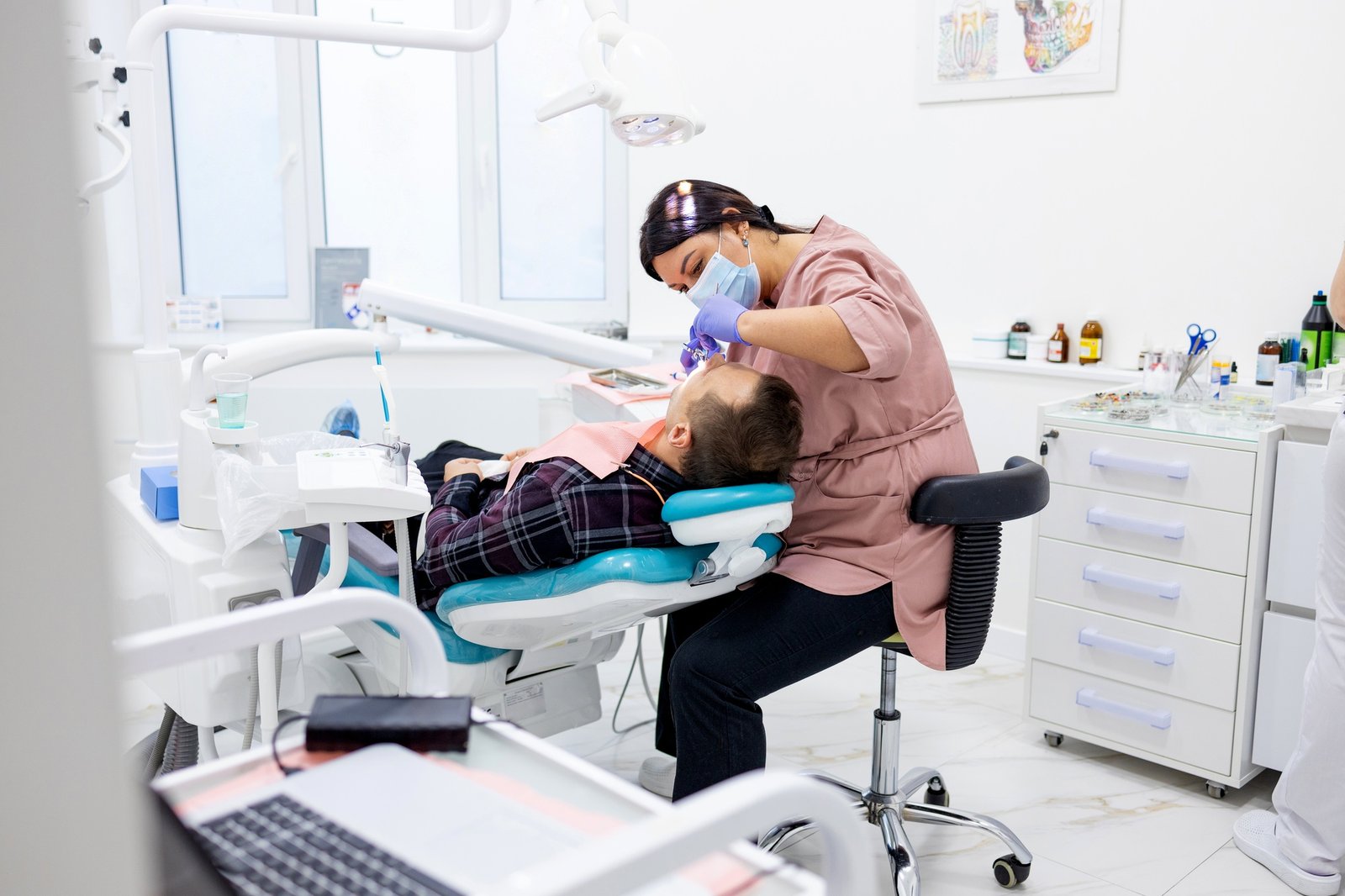 Side view of female dentist examining male patient with tools in dental clinic