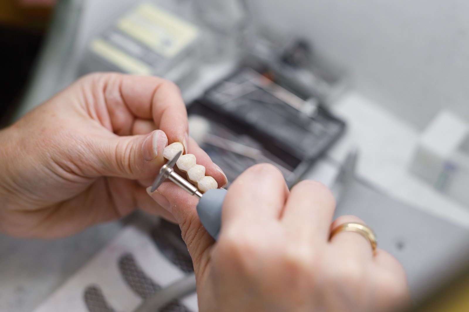 Technician working on prosthetic bridge with drill.